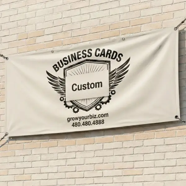 Custom cream-colored vinyl banner with an industrial wing logo and contact number, mounted to a light brick wall using reinforced grommets.